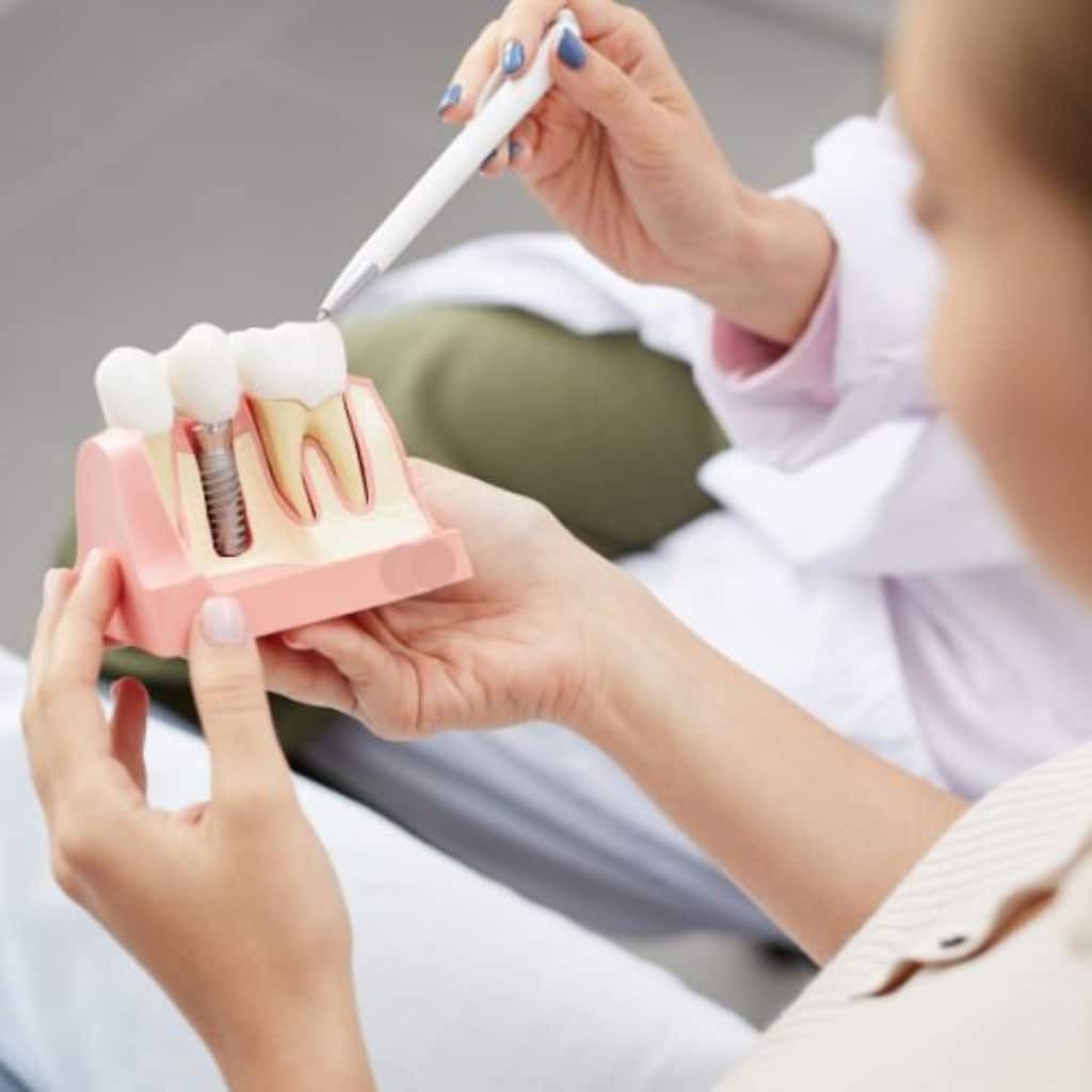 Dental professional demonstrating dental implant model to patient in Bellevue.