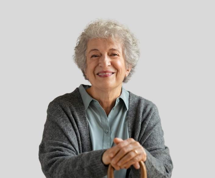 Smiling senior woman with gray hair wearing a cardigan and light blue shirt.